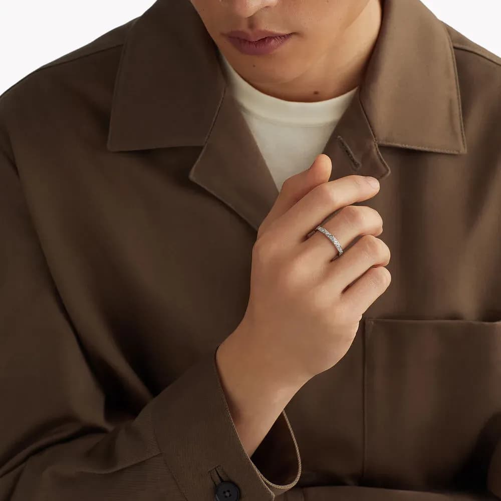 The ring worn on a hand, against a brown jacket